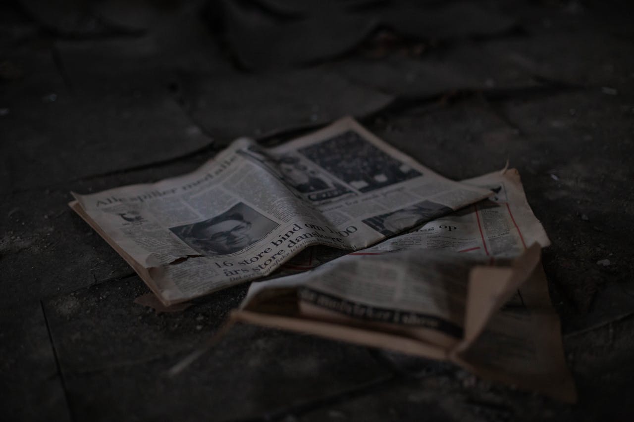 Scattered newspapers on an outdoor pavement, showcasing decay and abandonment.