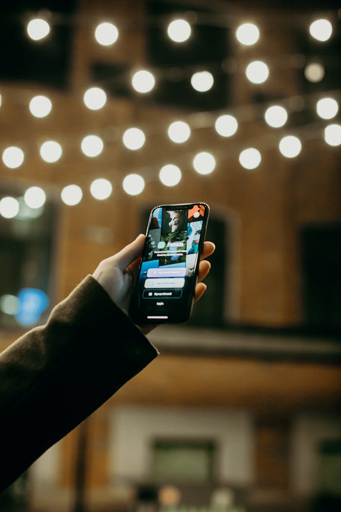 services-03 A hand holding a smartphone in a city at night, with blurred street lights.